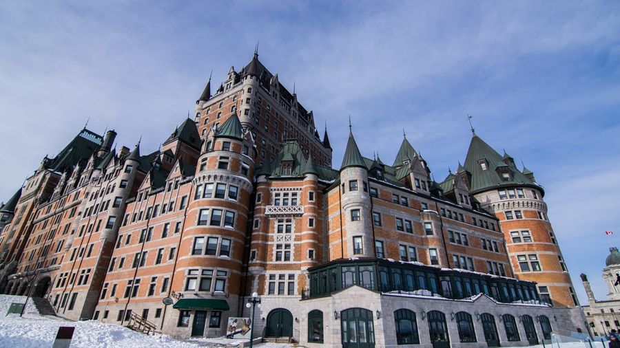 The Château Frontenac hotel rising above the snow-covered rooftops of Old Quebec on a clear winter day, with the frozen St. Lawrence River beyond