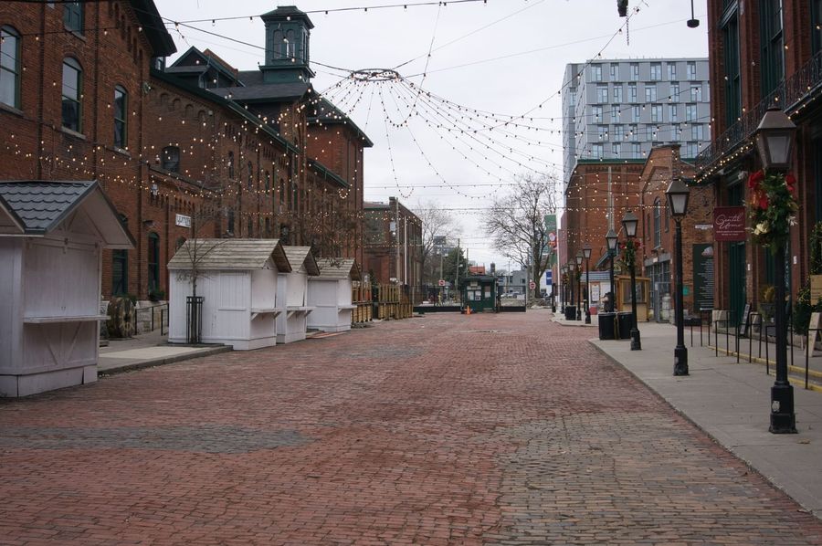 Cobblestone pedestrian lane of Toronto's Distillery District lined with Victorian red-brick warehouses and overhead string lights, a classic walking-tour setting